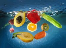 Фрукты и овощи: манго, киви, цуккини, морковь, болгарский перец, падают в чистую прозрачную воду, летят брызги.